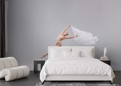 Portrait of young tender ballerina dancing with fabric isolated over grey studio background. Theatrical performance Wall mural