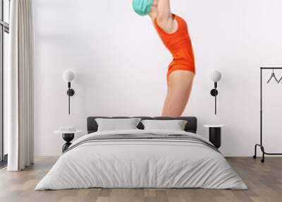 Portrait of young woman in swimming suit and cap jumping into water isolated over grey studio background Wall mural