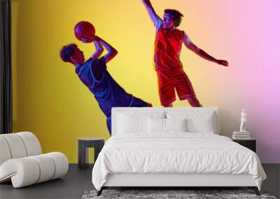 Two players practice basketball under vivid lights, capturing their skill and determination in dynamic in neon light against gradient studio background. Concept of sport, competition, match, team. Ad Wall mural