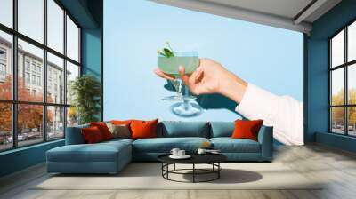 Women hand holding glass with margarita cocktail on light blue pop art background. Copy space for ad. Wall mural