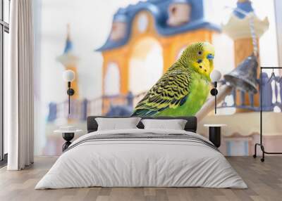 Funny budgerigar. Cute green budgie parrot sits on wooden stairs near toy castle and plays with bell. Wall mural