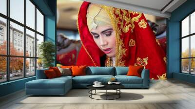 Portrait of young and beautiful Asian bride wearing traditional dress sitting with hands praying gesture and eyes closed in Minangkabau muslim tradition culture wedding ceremony. Wall mural