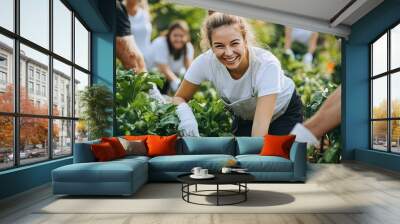 A woman smiles while working in a garden, surrounded by other volunteers. Wall mural