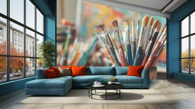 Close-up of a paintbrush holder with paintbrushes of various sizes, paint splatters, and a blurred colorful background. Wall mural