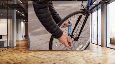 Man fixing a blue fixie bike wearing jeans and a black coat Wall mural