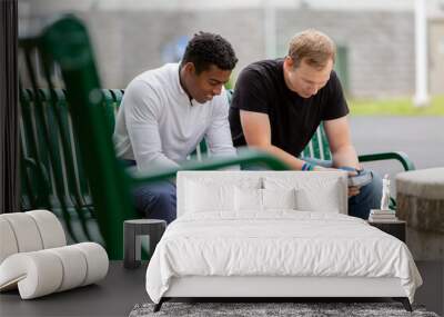 Two men sitting on a park bench praying together Wall mural