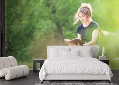 Young woman reading Bible on bench Wall mural