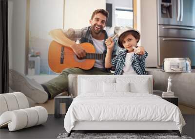 Are you ready for an encore. Portrait of a happy father accompanying his young son on the guitar while he drums on a set of cooking pots. Wall mural