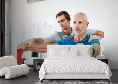 Keep your back straight. Shot of a young male physiotherapist helping a client with stretching exercises in his office during the day. Wall mural