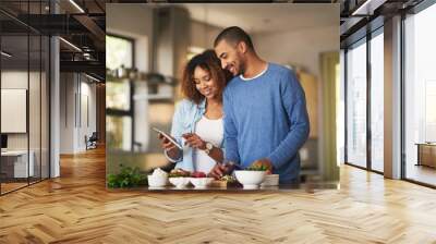 Using a step by step online recipe. Shot of a happy young couple using a digital tablet while preparing a healthy meal together at home. Wall mural