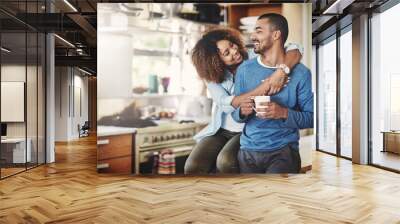 Romantic loving couple, smiling and enjoying a cup of coffee in the morning together at home in their kitchen. Carefree wife hugging and bonding with husband while relaxing looking in love Wall mural