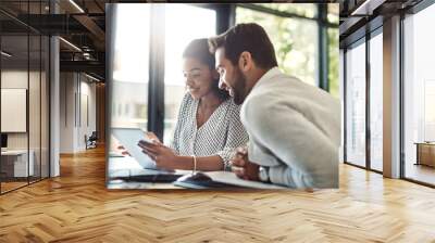 They always find a way to get things done. Shot of two businesspeople discussing something on a digital tablet. Wall mural