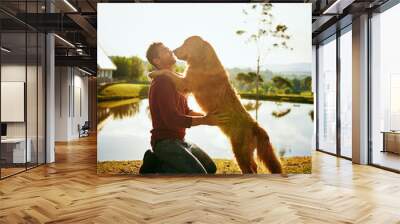 Whos a big boy. Full length shot of a handsome young man and his dog spending the day by a lake in the park. Wall mural