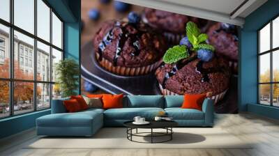 Chocolate muffins with chocolate syrup, blueberries and mint in a wooden background Wall mural