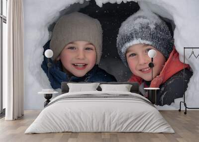 Two happy children peeking out from a snow cave, smiling joyfully during a winter adventure
 Wall mural