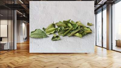 Heap of kaffir lime leaves lying on grey concrete background with copy space, side view Wall mural