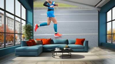 Marathon runner legs running on city road Wall mural