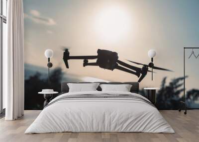 Silhouette of flying drone taking photo over sunrise Wall mural