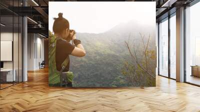 Woman photographer taking pictures on top of summer mountains Wall mural