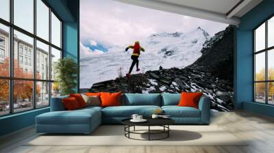 Woman trail runner cross country running up to winter snow mountain top Wall mural