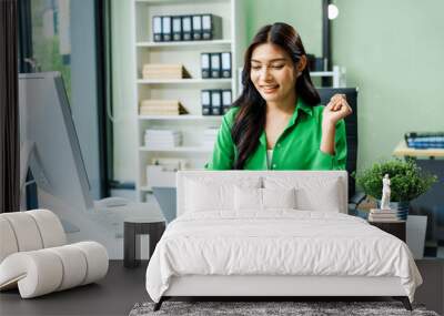 successful and happy young Asian businesswoman in a formal suit works at her desk in a modern glass office. consults on business strategies LGBTQ inclusivity, managing multiple projects efficiently. Wall mural