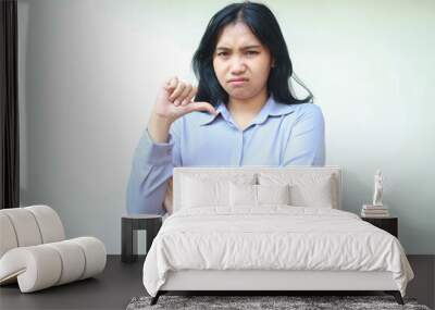 confused asian young business woman giving thumbs down looking aside with folded arm show upset expression felling dissatisfied wearing formal shirt standing over isolated white background Wall mural