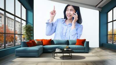 excited asian woman talking on smartphone and pointing finger show presenting gesture wearing striped shirt isolated on white background Wall mural