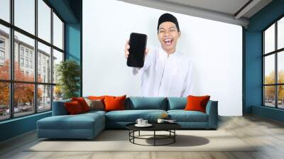 happy asian muslim man showing blank phone screen with laugh Wall mural