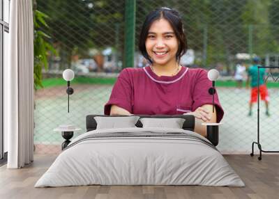 happy asian woman standing in tennis court with cross arms look at camera with confidence Wall mural