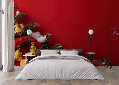 Cozy red festive decor with golden bells, snow, candles, and a knitted blanket against a deep red background Wall mural