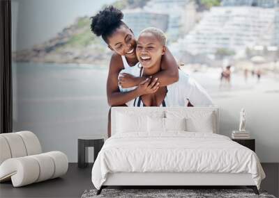 LGBTQ, gay and lesbian black women enjoying a piggyback ride and fun at beach in summer. Friends, dating and trust with female and her girlfriend on holiday, vacation or travel by the coast Wall mural