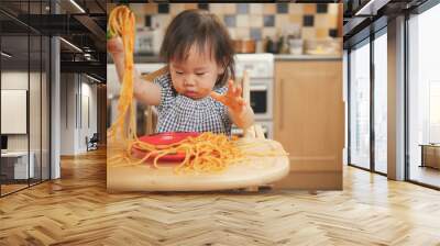 baby girl eating messy spaghetti at home Wall mural