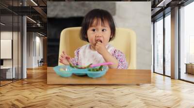 baby girl eating vegetable at home Wall mural