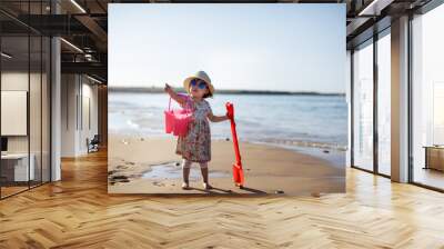 baby girl wearing sunglasses running on the summer beach Wall mural