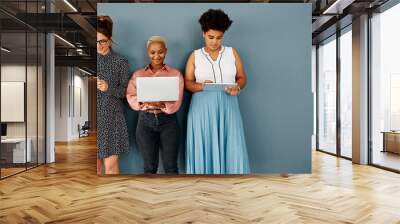 Youll need to byod to join them. Studio shot of a group of attractive young businesswomen using wireless technology while standing against a grey background. Wall mural