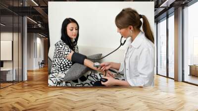 female doctor measures patient's blood pressure Wall mural