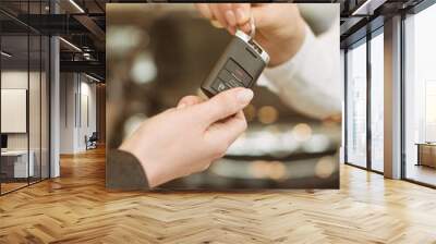 Female hand getting modern car key on a car background Wall mural