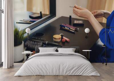 Woman doing makeup in front of a mirror at home. Wall mural