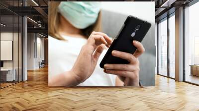 woman in medical mask using mobile phone. isolation at home. Wall mural