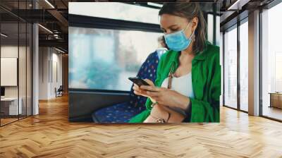 Woman in medical mask with mobile phone in the bus. Wall mural