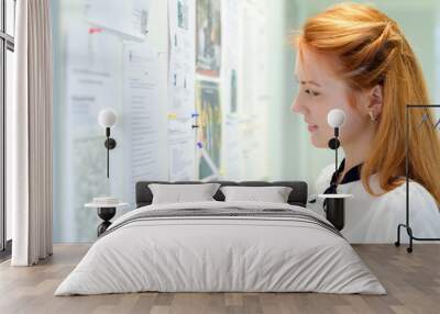 young female student looking through job offers on board Wall mural