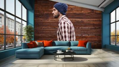 Styled for the street. Shot of a handsome young man in trendy winter attire against a wooden background. Wall mural