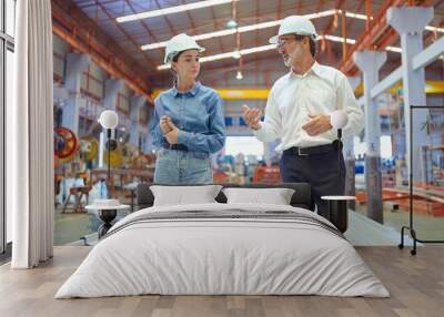 Two professional engineer man and woman manager leader wearing helmet and walking in factory talking and discussing for work Wall mural