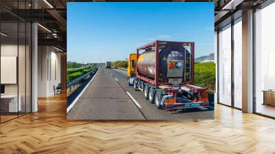 Truck driving on a highway with a tank container with labels and danger panels for toxic liquids according to the international treaty on dangerous goods. A.D.R. Wall mural