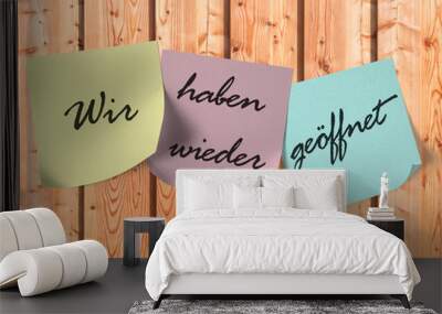 Klebezettel mit dem Text ,Wir haben wieder geöffnet,auf einer Holzwand Wall mural