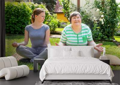 yogalehrerin und geistig behinderte frau sitzen im garten, entspannungsübungen und sonderpädagogik Wall mural