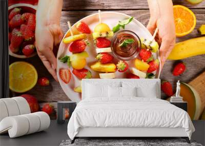 hand holding platter with fruit skewer and chocolate Wall mural