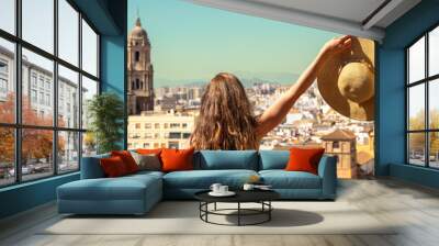 Rear view of woman with hat looking at panoramic skyline of Malaga city- Spain Wall mural