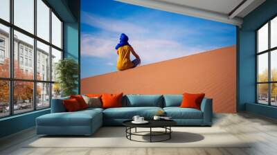 Woman sitting on sand dune in Sahara desert- travel, adventure, wanderlust concept Wall mural