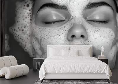 Black-and-white portrait of a beautiful woman with closed eyes, her face covered in soap foam for a facial treatment, a spa concept. Wall mural